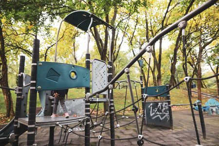 Little girl playing and climbing in an empty children playground in a public park