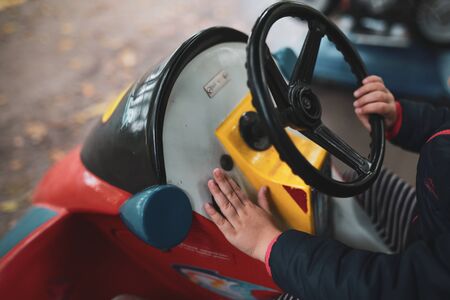 Shallow depth of field (selective focus) image with the hand of a little girl on a toy car in a public parkの写真素材