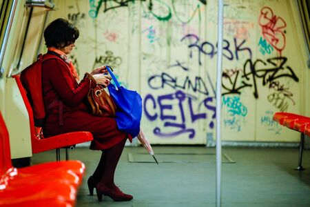 Bucharest, Romania - November 19, 2019: A woman is travelling in a dirty and old metro wagon full of graffiti.のeditorial素材