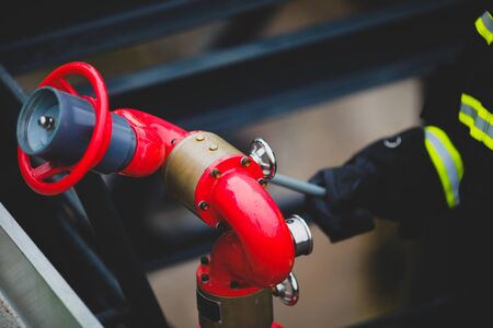 Details with the hands of a firefighter holding a fire suppression system (hydrant) on a hospital helipad.の写真素材