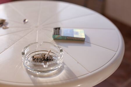 Shallow depth of field image with a dirty glass ashtray on a table - stop smoking concept.の写真素材