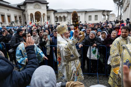Bucharest, Romania - January 6, 2020: Romanian Orthodox Patriarch Daniel sprinkles holy water over believers at the end of the Epiphany mass, outside the patriarchal palace.のeditorial素材