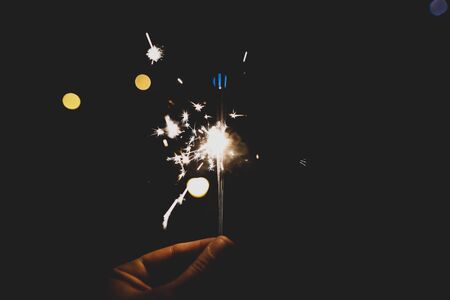 Details with the hand of a man holding sparklers hand fireworks.
