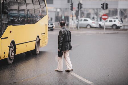 Old man illegally crossing the road in the middle of a crossroad.の写真素材