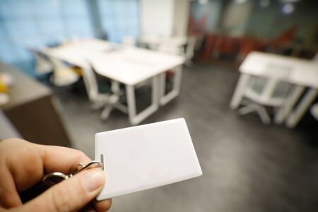 Shallow depth of field (selective focus) image with the hand of a man holding an access card inside an office building.の写真素材