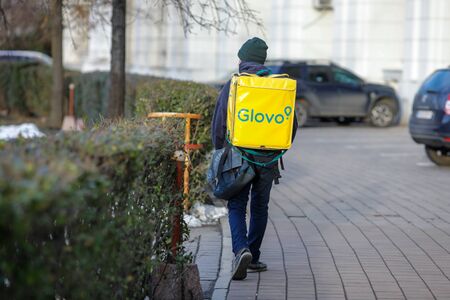 Bucharest, Romania - February 12, 2020: Man carrying a Glovo delivery backpack on the streets of Bucharest.のeditorial素材