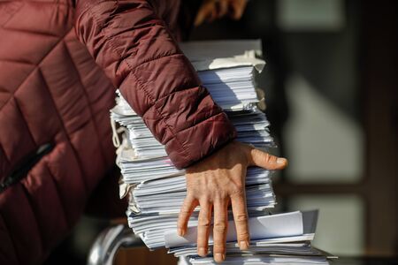 Shallow depth of field (selective focus) image with the hands of a man picking up a pile of files.