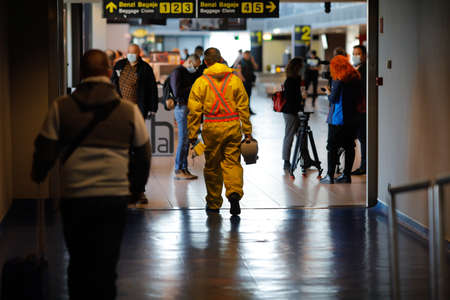 Otopeni, Romania - February 25, 2020: People wearing protective suits spray disinfectant chemicals on the Henri Coanda International Airport to prevent the spreading of the coronavirus.のeditorial素材