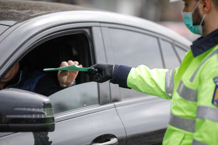 Bucharest, Romania - March 25, 2020: Romanian road police officer pulls over a car to check for the...