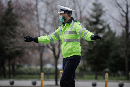 Bucharest, Romania - March 25, 2020: Romanian road police officer pulls over a car to check for the...