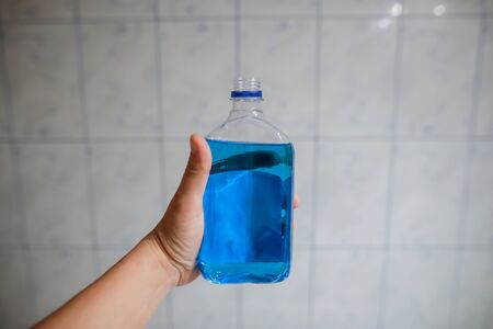 Shallow depth of field image (selective focus) with the hand of a man holding a plastic bottle of spirt - Romanian medical alcohol used for disinfection.の写真素材