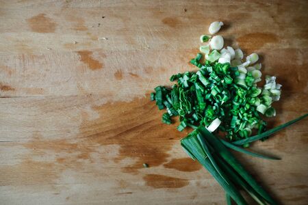 Shallow depth of field (selective focus) image with chopped spring onions on a wooden cutter.の写真素材