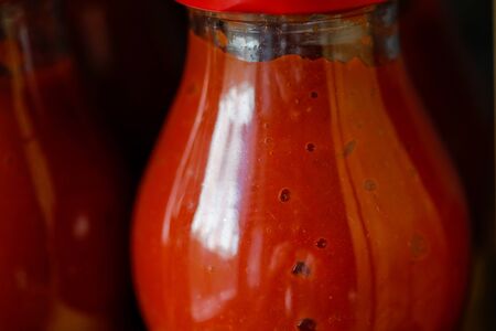 Shallow depth of field (selective focus) details with tomato paste in a a glass bottle on the shelf in the home pantry.の写真素材