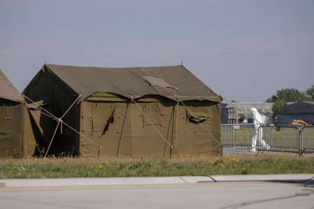 Otopeni, Romania - April 25, 2020: People wearing protective suits for covid-19 near a military tent on an army airport.のeditorial素材