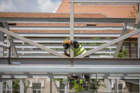 Bucharest, Romania - May 8, 2020: Construction workers on a construction site with protective masks due to the Covid-19 outbreak.のeditorial素材