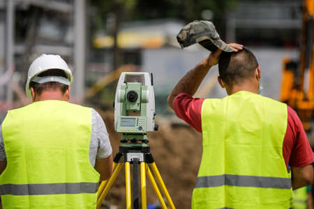 Bucharest, Romania - May 8, 2020: Topography engineers on a construction site with protective masks due to the Covid-19 outbreak.のeditorial素材