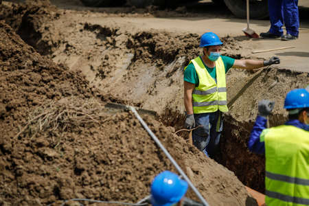 Bucharest, Romania - May 8, 2020: Construction workers on a construction site with protective masks due to the Covid-19 outbreak.のeditorial素材
