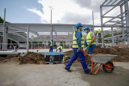 Bucharest, Romania - May 8, 2020: Details with a construction worker pushing a wheelbarrow on a...