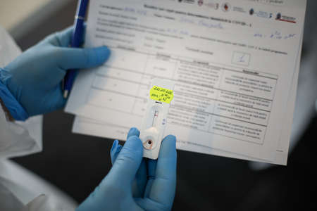Bucharest, Romania - June 10, 2020: Details with the hands of a health official holding a fast Covid-19 Antibody Test (past infection).のeditorial素材