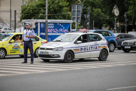 Bucharest, Romania - June 13, 2020: Romanian police officer near a police car in downtown Bucharest.のeditorial素材