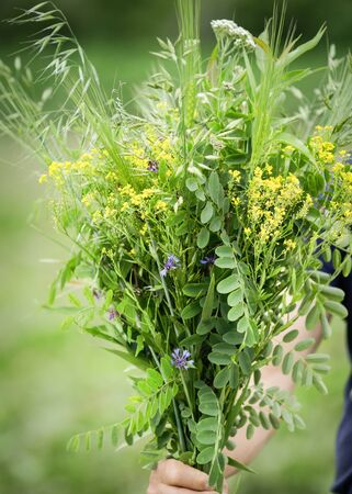 Details with the hand of a man holding a bouquet of wild flowers.の写真素材