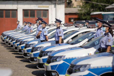 Bucharest, Romania - July 29, 2020: Romanian Police officers wearing masks pose next to new Dacia cars on display during an event of the Police Force.のeditorial素材
