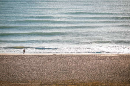 Man walking on a Black Sea beach during a pleasant late summer sunrise.