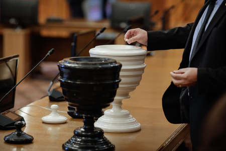 Bucharest, Romania - October 27, 2020: Details with Romanian MP casting a secret vote with black and white balls (Blackballing) in black and white urns - secret ballot.のeditorial素材
