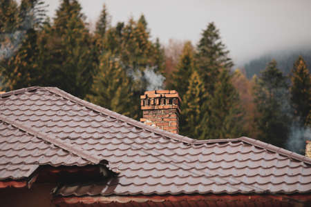 Smoking red brick chimney with a cone trees forest in the background, in a mountain area of Romania...