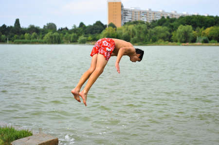 Bucharest, Romania - July 18, 2010: Teenage boy jumps into the water of a lake in a public park during a hot summer day.のeditorial素材