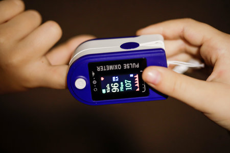 Details with the hands of a little girl measuring her pulse and blood oxygen level with a self use pulse oximeter at home during the Covid-19 outbreak.のeditorial素材