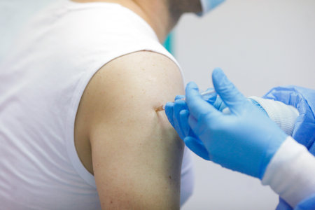 Details with a man getting an intramuscular injection with the Sars-Cov-2 vaccine in a hospital from a medical worker.の写真素材