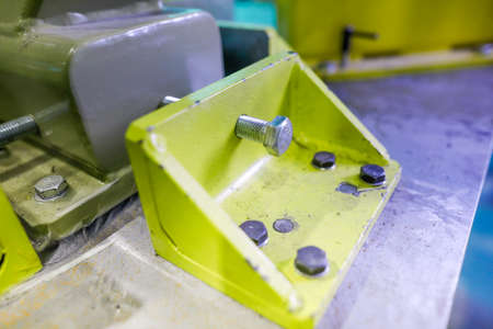 Shallow depth of field (selective focus) image with details of industrial metallic nuts and bolts in...