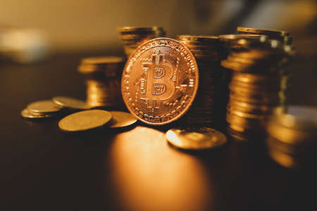 Shallow depth of field (selective focus) image with a Bitcoin metal coin near other metal coins -...