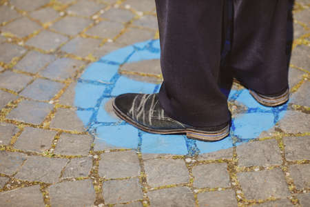 Shallow depth of field (selective focus) details with feet of people standing on special spots for social distancing at an event, during the Covid-19 outbreak.の写真素材