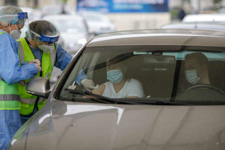 Bucharest, Romania - April 29, 2021: A woman is getting Covid-19 vaccine in his arm in his car, in a drive thru vaccination centre in Bucharest, Romania.のeditorial素材