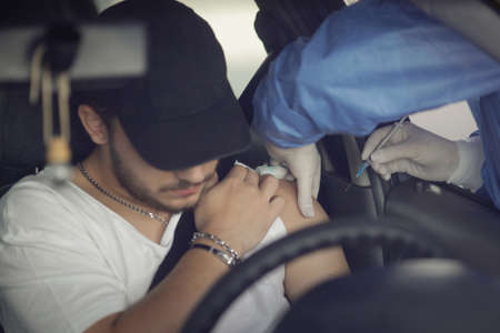 Bucharest, Romania - May 22, 2021: A man is getting Covid-19 vaccine in his arm in his car, in a drive thru vaccination centre in Bucharest, Romania.のeditorial素材