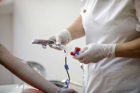 Shallow depth of field (selective focus) details with the hands of a medical worker preparing a volunteer for donating blood.の写真素材