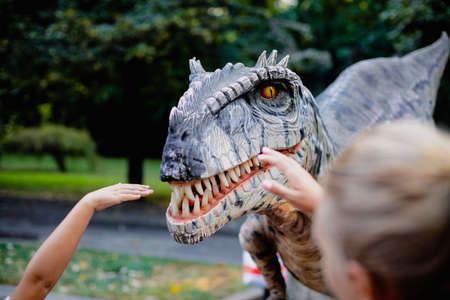 Bucharest, Romania - August 29, 2021: A man costumed as a carnivorous dinosaur walks between people...