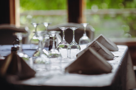 Shallow depth of field (selective focus) image with a restaurant table ready to receive customers. Empty glasses and tableware.の写真素材