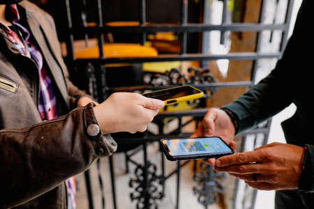 Bucharest, Romania - September 23, 2021: Shallow depth of field (selective focus) image with a restaurant client showing a Covid-19 certificate from a mobile phone to an employee.のeditorial素材