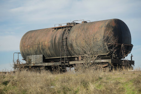Shallow depth of field (selective focus) image with old and rusty railway oil tanker in the middle of a field on a sunny winter day.の写真素材