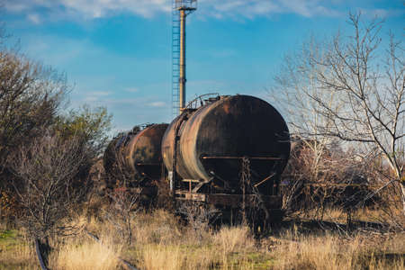 Shallow depth of field (selective focus) image with old and rusty railway oil tankers in the middle of a field on a sunny winter day.の写真素材