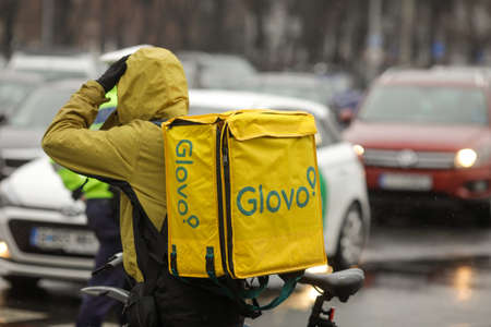 Bucharest, Romania - December 17, 2021: Man carrying a Glovo delivery backpack on the streets of Bucharest.のeditorial素材