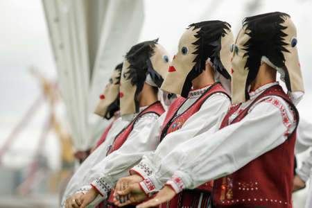 Braila, Romania - August 26, 2021: Women dressed in Romanian traditional costumes and with ritual double face masks perform a traditional dance.のeditorial素材