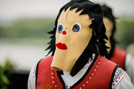 Braila, Romania - August 26, 2021: Woman dressed in Romanian traditional costumes and with ritual double face mask performs a traditional dance.のeditorial素材