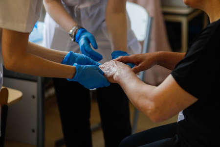 Details with the hands of a female medic and a female resident medic checking the dermatological health of a woman.の写真素材
