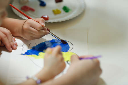 Bucharest, Romania - May 9, 2022: Shallow depth of field (selective focus) details with Ukrainian refugee children drawing Ukrainian heart shaped flags.のeditorial素材