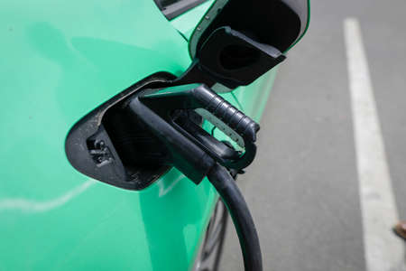 Shallow depth of field (selective focus) details with auto electric plug or socket at an electric vehicle charging station.の写真素材