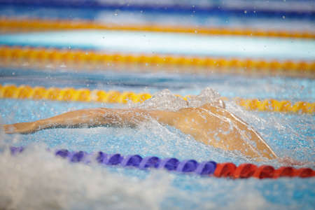 Details with a professional male athlete swimming in a swimming pool.